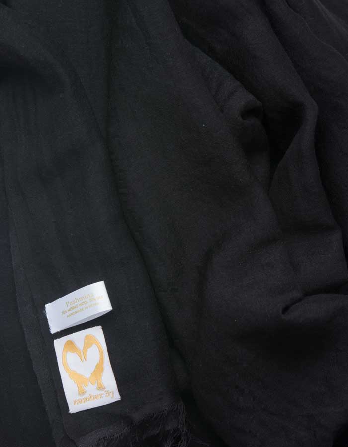 A close up image of a wool silk mix pashmina in Black