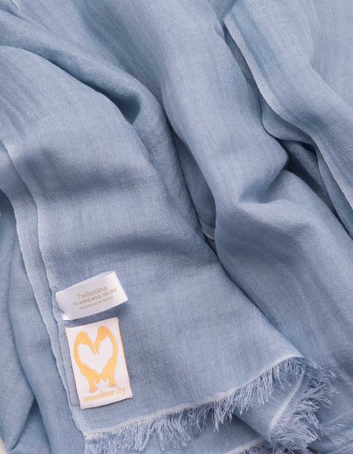 A close up image of a wool silk mix pashmina in blue