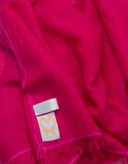 A close up image of a wool silk mix pashmina in hot pink
