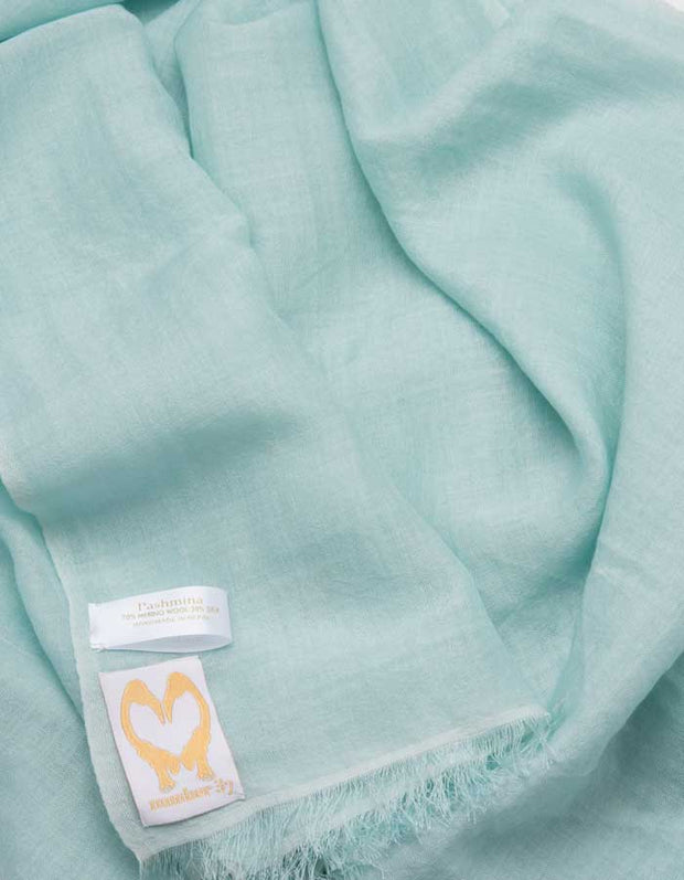A close up image of a wool silk mix pashmina in mint green