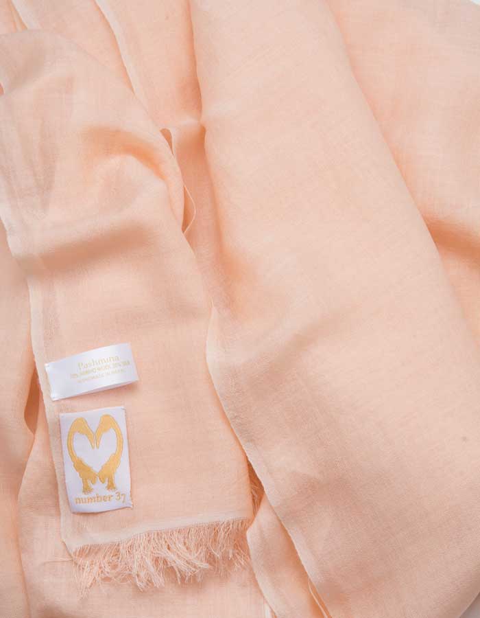 A close up image of a wool silk mix pashmina in peach