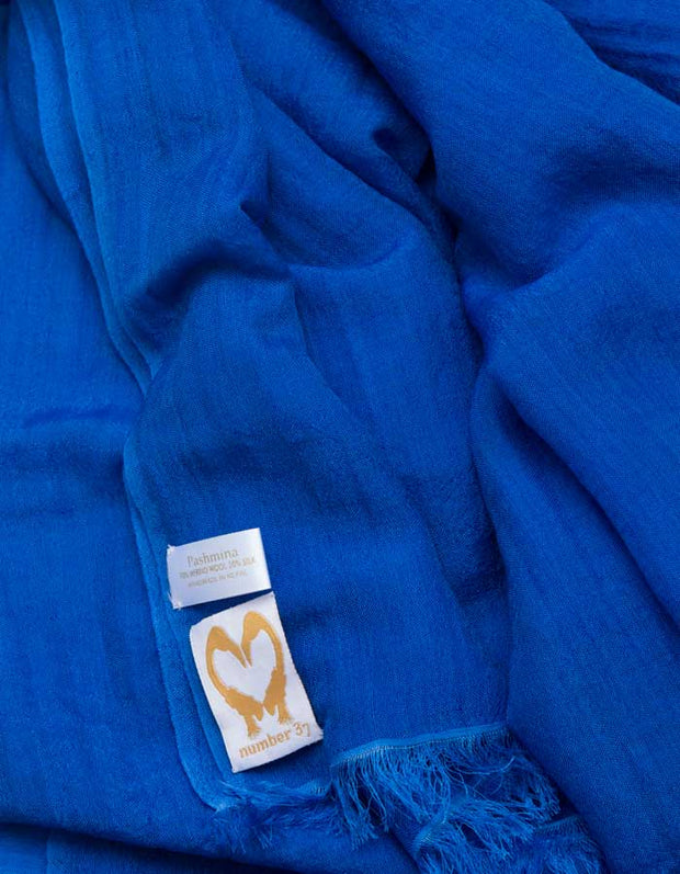 A close up image of a wool silk mix pashmina in Royal blue